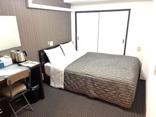 a hotel room with a bed and a desk and a desk at Business Inn Sennichimae Hotel in Osaka