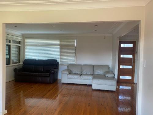 a living room with a couch and a chair at Comfortable Room in Spacious Greenacre Home - GA1 in Chullora