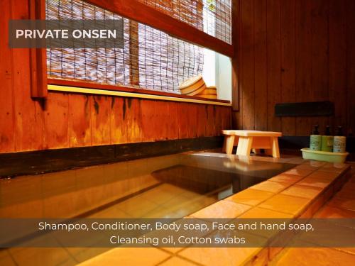 a room with a bench and a window and a table at BUNA KUSATSU Onsen Inn in Kusatsu