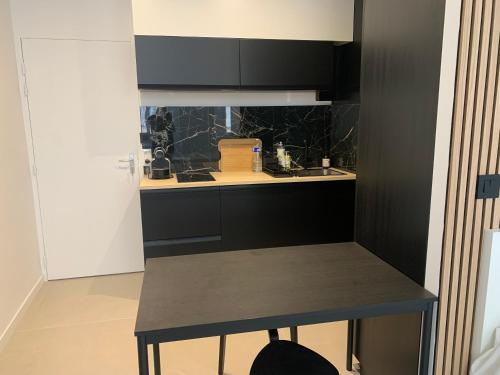 une cuisine avec des armoires noires et une table. dans l'établissement Studio au cœur d Aix en Provence, à Aix-en-Provence