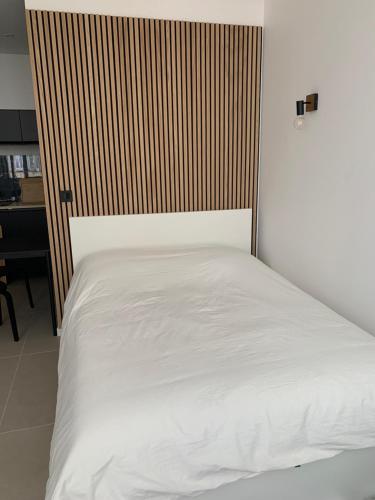 une chambre avec un lit blanc avec une tête de lit en bois dans l'établissement Studio au cœur d Aix en Provence, à Aix-en-Provence