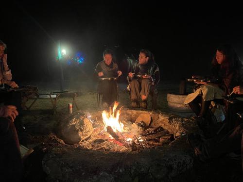a group of people sitting around a fire at Kunjapuri camps & Cottage in Narendranagar