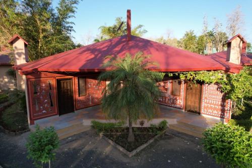 a house with a red roof with a palm tree in front at Palash Kothi -Bandhavgarh in Tāla