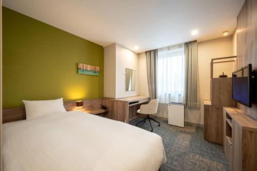 a hotel room with a white bed and a desk at ホテル仙台ガーデンパレス in Sendai