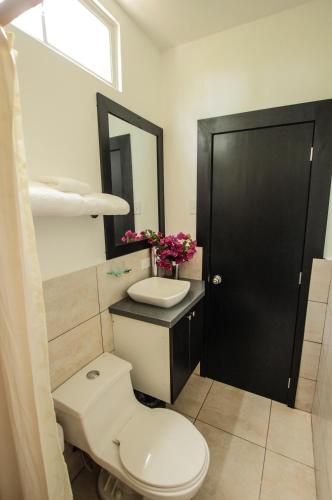 a bathroom with a toilet and a sink and a black door at Ocean Blue Hotel in Olón