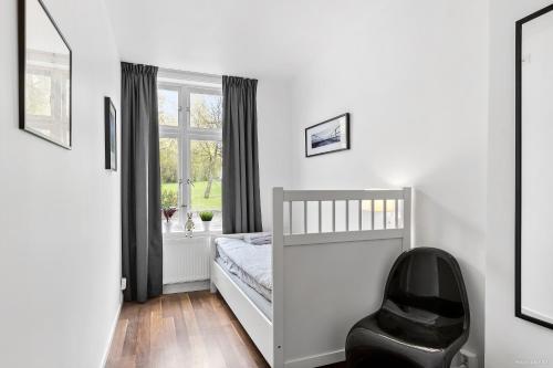a white bedroom with a bed and a black chair at HernöRum Franzéngatan - Centrala lägenheter in Härnösand
