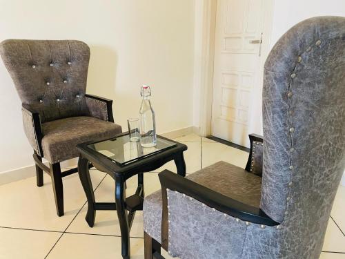 a living room with a table and two chairs and a bottle at Pine Wood Villa in Mānānwāla