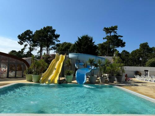 une piscine avec un toboggan aquatique dans un complexe hôtelier dans l'établissement Un toit sur le bassin Claouey, à Lège-Cap-Ferret