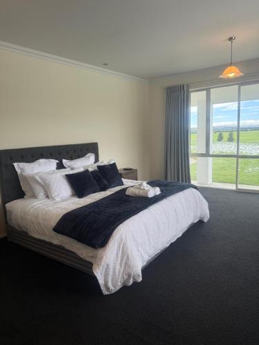 a bedroom with a large bed and a large window at Ruataniwha Lodge in Twizel