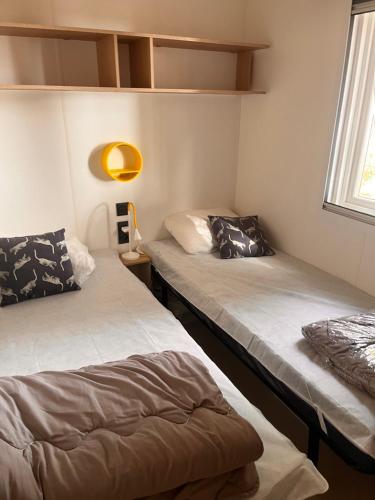 deux lits dans une chambre avec une fenêtre dans l'établissement Bungalow Mobil Home Carry-le-rouet, à Carry-le-Rouet