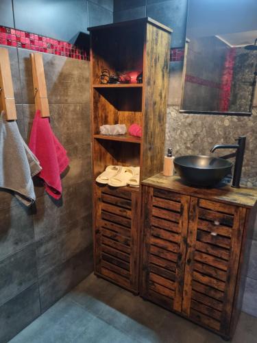 a bathroom with a sink and a bowl on a wooden cabinet at La Grange in Verlaine