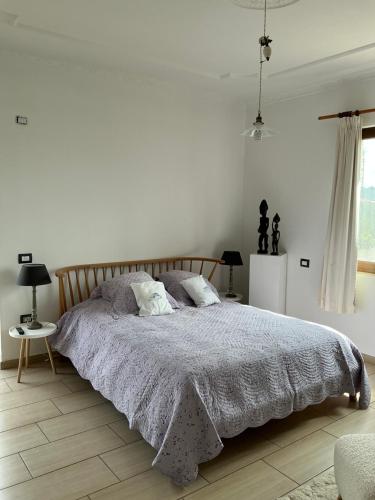 ein weißes Schlafzimmer mit einem Bett mit einer grauen Decke in der Unterkunft Hostel Calao in Shkodra