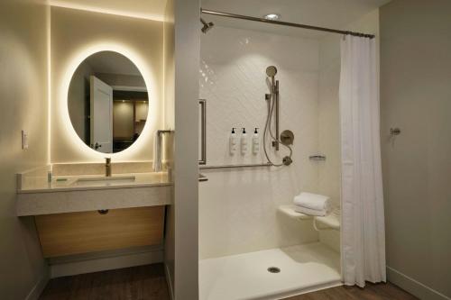 a bathroom with a shower and a sink and a mirror at TownePlace Suites by Marriott Fort Myers Southeast in Fort Myers