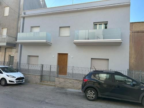 two cars parked in front of a white building at Appartamenti vista mare Otranto in Otranto