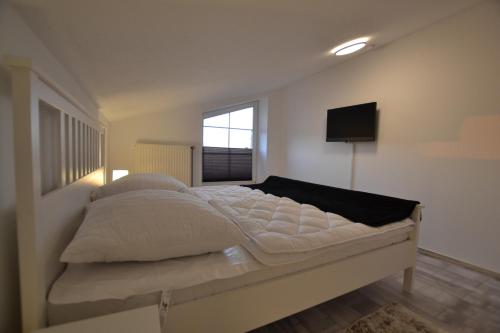 a bedroom with a bed with a television on the wall at FeWo Landkirchen 2 in Fehmarn