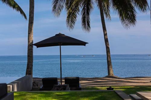 a beach with chairs and an umbrella and the ocean at Lombok Private Villa Estate in Ketapang