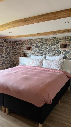 a bed in a room with a stone wall at Can Jan Vives in Vidreres