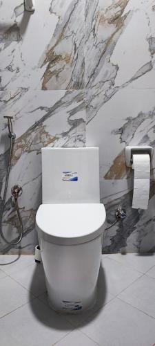 eine weiße Toilette in einem Badezimmer mit Marmorwand in der Unterkunft Villa 6 in Ajman 