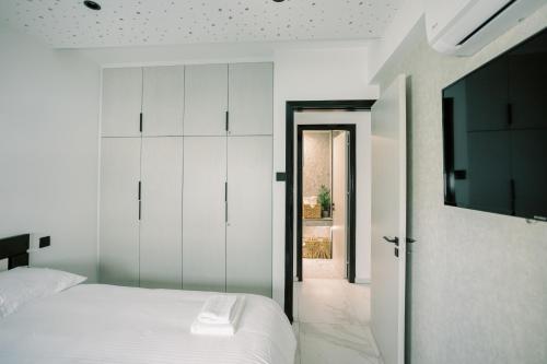 a bedroom with a white bed and a television at 2BR Amalfi Blue Apt in Larnaca - Pool & 10Min Walk to Mackenzie Beach! in Larnaca