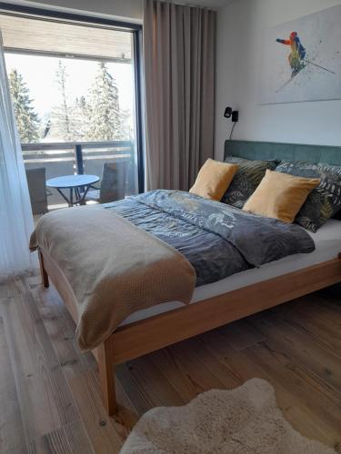 a bed in a bedroom with a large window at Modern Alpine Apartment Corso Harrachov in Harrachov