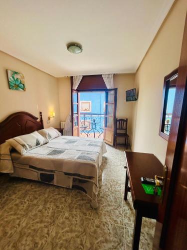 a bedroom with a bed and a table and a window at Hotel las Palmeras Suite in Celorio