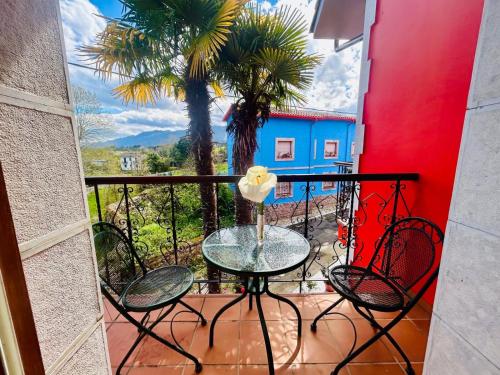 a table and chairs on a balcony with a palm tree at Hotel las Palmeras Suite in Celorio