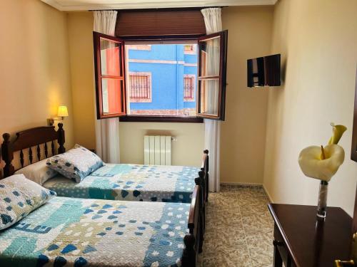a bedroom with two beds and a window at Hotel las Palmeras Suite in Celorio