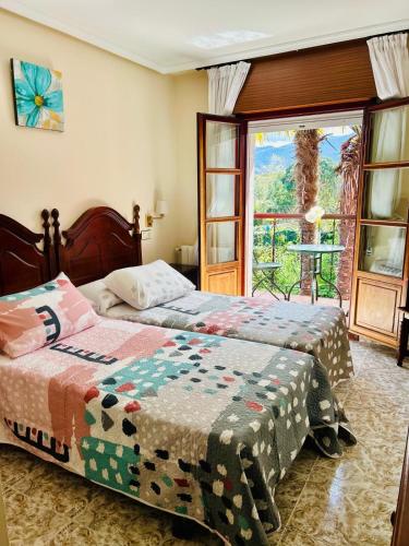 a bedroom with two beds and a large window at Hotel las Palmeras Suite in Celorio