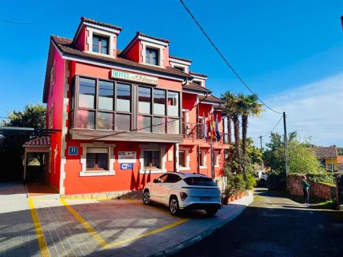a car parked in front of a red building at Hotel las Palmeras Suite in Celorio