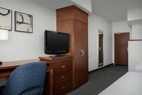 a room with a tv and a desk with a chair at Courtyard by Marriott Salisbury in Salisbury
