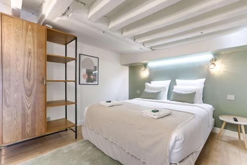 une chambre avec un grand lit blanc et une table dans l'établissement Residence - Roquette - Marais, à Paris