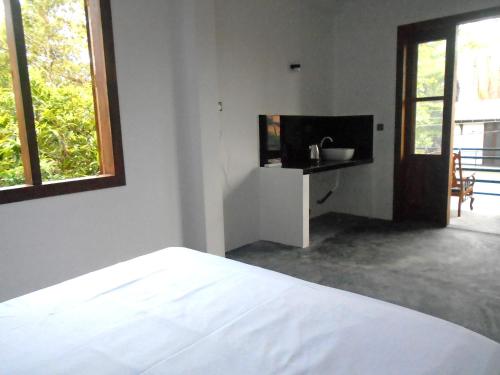 a white bedroom with a bed and a television at Sea Wawes Hiriketiya in Hiriketiya