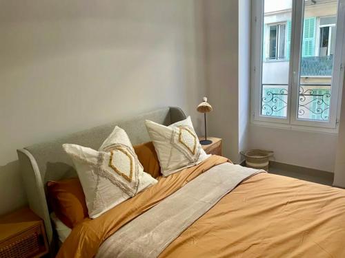 a bed with white pillows and an orange blanket at Suite Massena in Nice