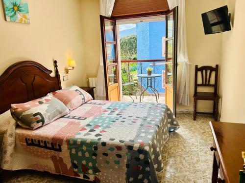 a bedroom with a bed and a door to a balcony at Hotel las Palmeras Suite in Celorio