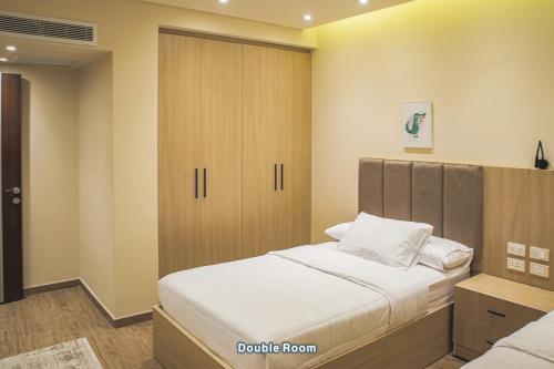 a bedroom with a bed and a wooden cabinet at شقة فندقية الشيخ زايد - Zayed Suites F in Sheikh Zayed