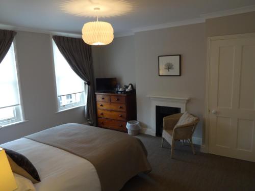 a bedroom with a bed and a chair and windows at Ogilvy House in Cromer