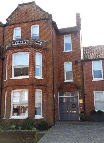 a red brick house with a black door at Ogilvy House in Cromer