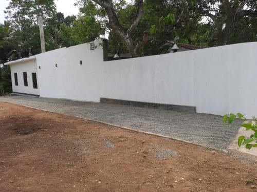 a white wall next to a dirt road at Black Rose Guest in Gampaha