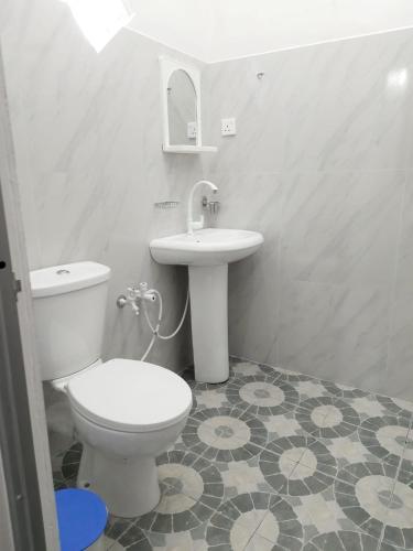 a bathroom with a white toilet and a sink at Black Rose Guest in Gampaha