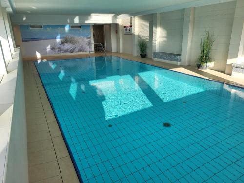 a large swimming pool with a blue tiled floor at LITTLE SKYSUITE Terrassenhaus W 94 in Cuxhaven