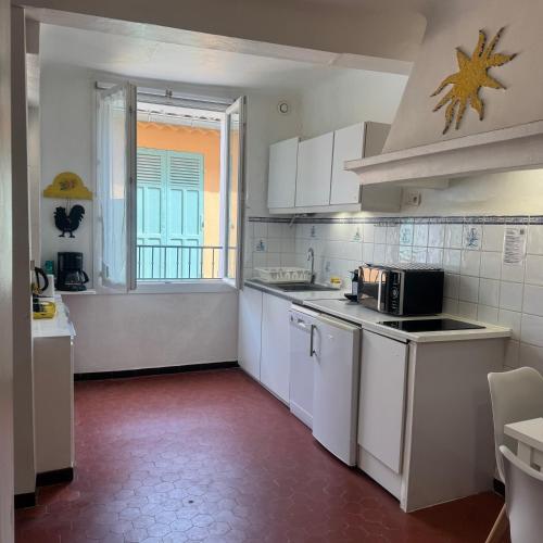 d'une cuisine avec des placards blancs, une fenêtre et un évier. dans l'établissement Studio Gambetta Saint-Tropez, à Saint-Tropez