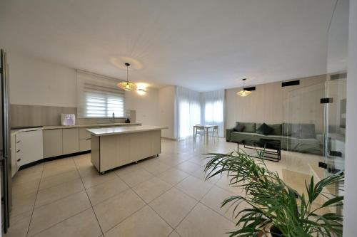 a large kitchen and living room with a couch at פנטהאוז 125 - פנטהאוז, דירת אירוח וגג מהמם לאירועים עם בריכה וגקוזי in Nahariyya