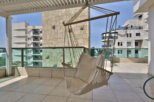 a hammock on the balcony of a building at פנטהאוז 125 - פנטהאוז, דירת אירוח וגג מהמם לאירועים עם בריכה וגקוזי in Nahariyya