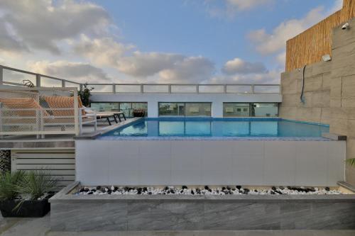 a swimming pool with a patio and a house at פנטהאוז 125 - פנטהאוז, דירת אירוח וגג מהמם לאירועים עם בריכה וגקוזי in Nahariyya