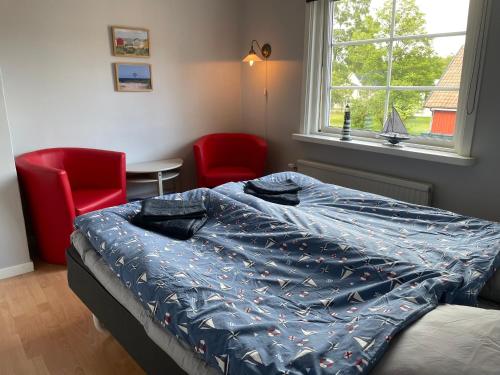 a bedroom with a bed and two red chairs at Sjökaptensgården Bed & Breakfast in Åsljunga