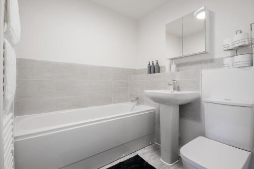 a white bathroom with a sink and a tub and a toilet at Flat in Milton Keynes Free parking Self checkin fast wifi in Milton Keynes