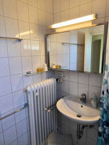 a bathroom with a sink and a mirror and radiator at Ferienwohnung König in Dornstadt