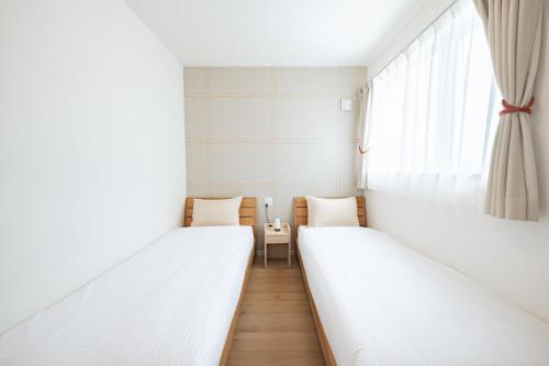 two beds in a room with a window at Furano Ezo Murasaki A in Furano