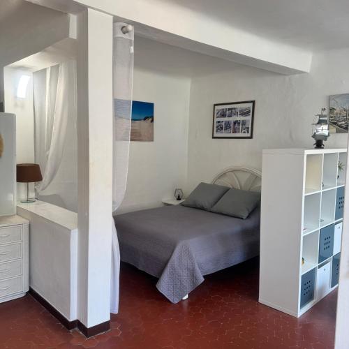 une chambre avec un lit dans une pièce blanche dans l'établissement Studio Gambetta Saint-Tropez, à Saint-Tropez
