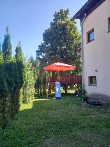 a table with a red umbrella in a yard at U Fary in Jestrabi V Krkonosich